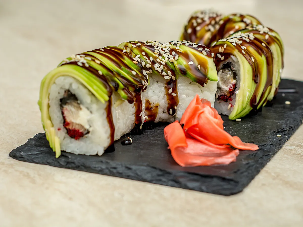 Avocado-topped sushi rolls with eel sauce and sesame seeds